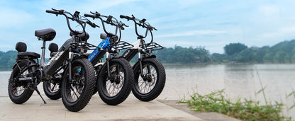 Four electric bikes parked by a body of water with trees in the background
